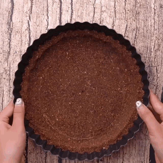 a person is holding a pie pan with a brown crust