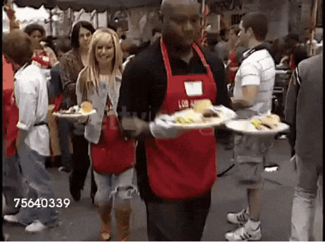 a man in a red apron is carrying a plate of food