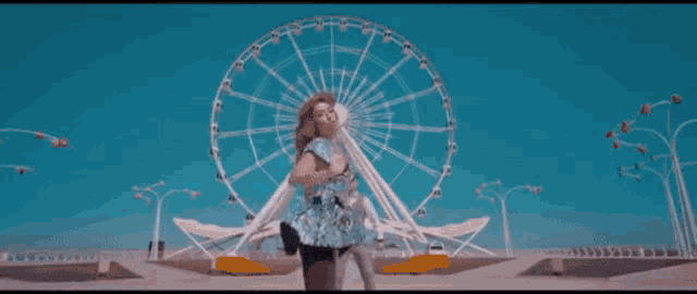 a woman is standing in front of a ferris wheel in an amusement park .