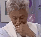 a man in a robe is covering his mouth with his hand while wearing a ring .