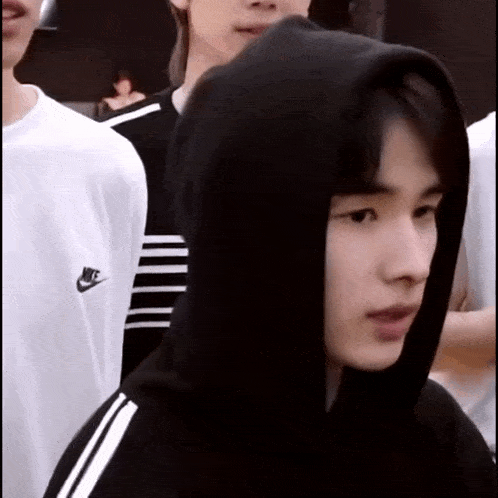 a man wearing a black nike hoodie is standing in a crowd