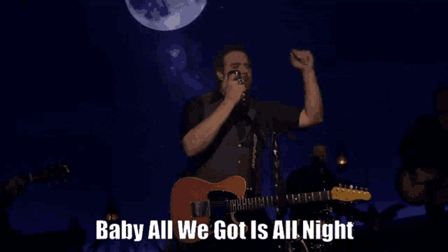 a man singing into a microphone while playing a guitar with the words baby all we got is all night above him