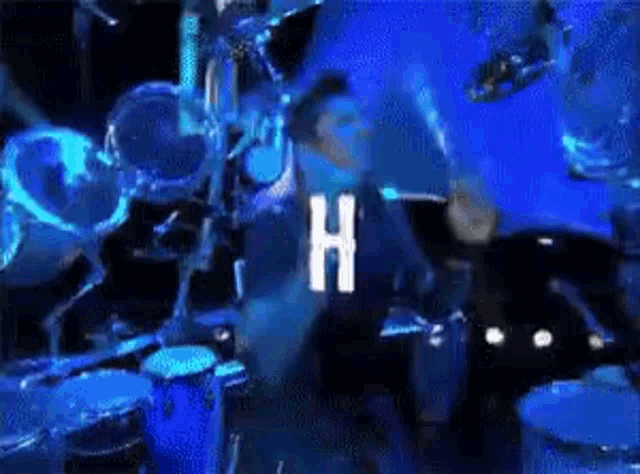 a man is playing drums in front of a drum set in a dark room .