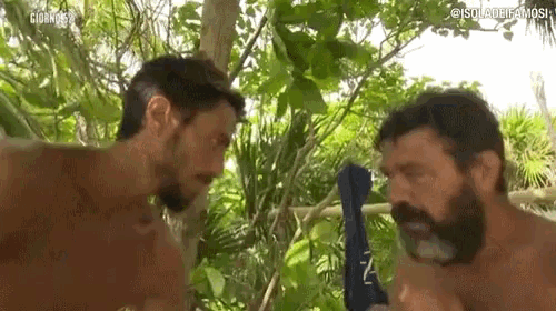 two men are standing next to each other in the jungle .