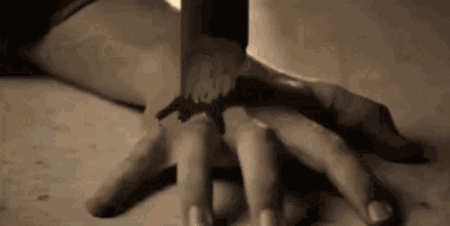 a close up of a person holding another person 's hand on a table .
