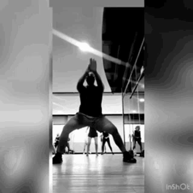 a black and white photo of a man doing a yoga pose in a gym