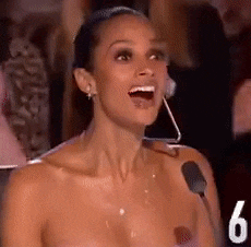 a woman without a shirt is singing into a microphone with the number 6 behind her .