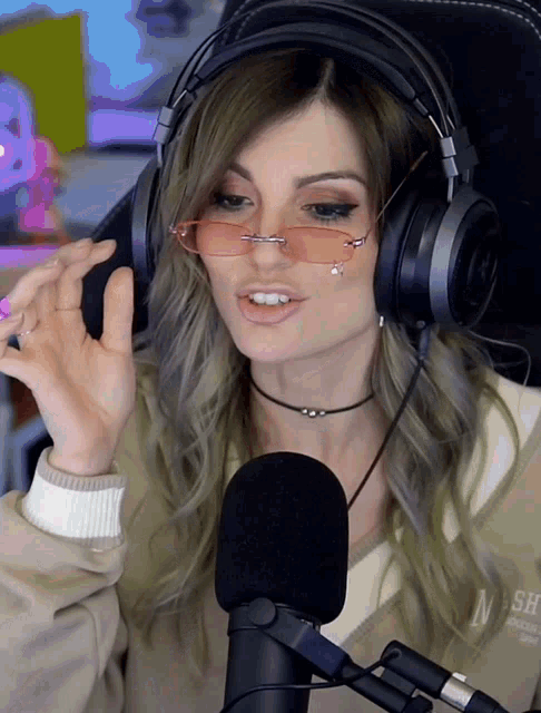 a woman wearing headphones and pink sunglasses is talking into a microphone