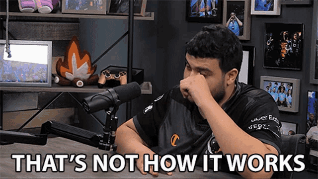a man sitting in front of a microphone with the words that 's not how it works written below him