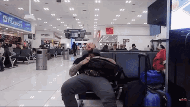 a man is sitting in a waiting area with a sign that says hudson