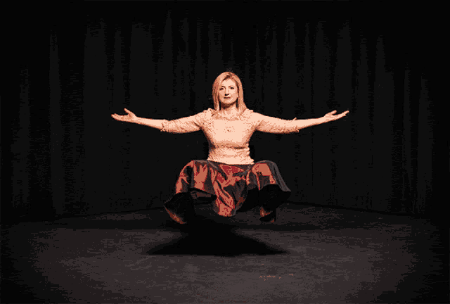a woman with her arms outstretched is wearing a red and black dress