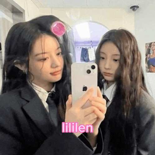 a girl with curlers in her hair is taking a picture of herself with another girl .