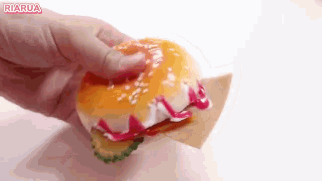 a person is holding a hamburger with ketchup and mustard on it .