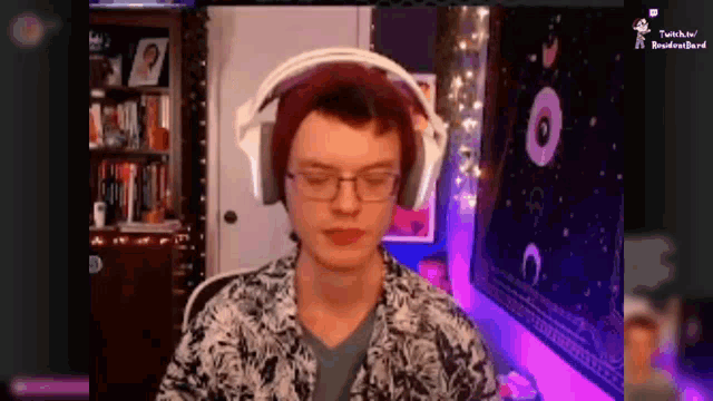 a man wearing headphones and a beanie is sitting in front of a computer .