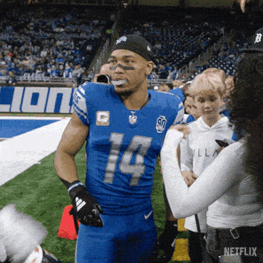 a football player wearing a blue uniform with the number 14 on it