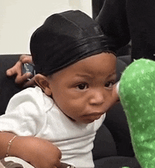 a baby wearing a black hat and a white shirt