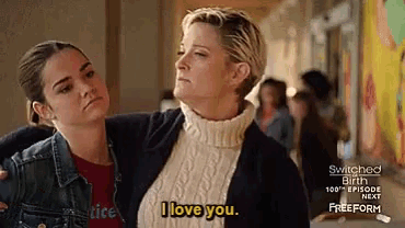 two women are standing next to each other and one of them says i love you .