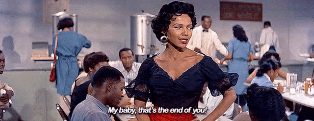 a woman in a black top and red skirt is standing in front of a group of people and says my baby