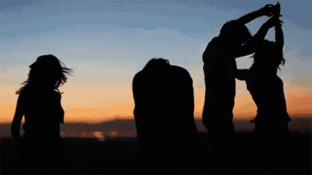 a group of people are dancing at sunset with mountains in the background