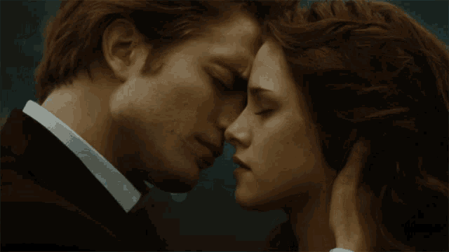 a man in a suit and tie kisses a woman in a white shirt