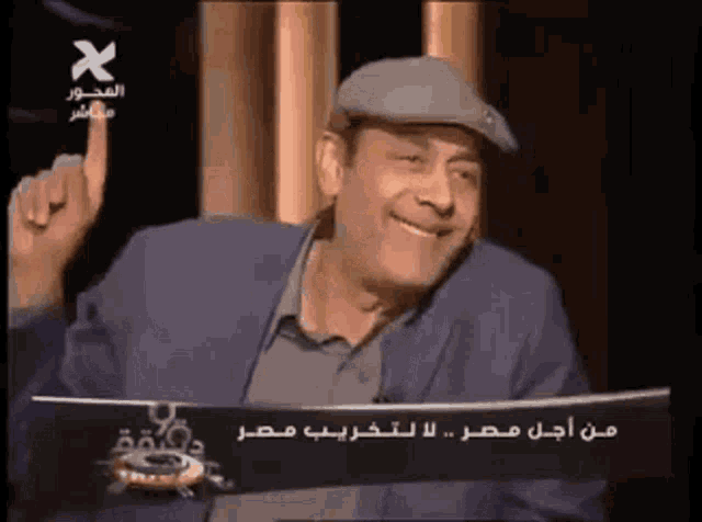 a man wearing a hat and a suit is smiling and pointing at something