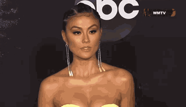 a woman is standing on a red carpet wearing a very revealing dress and earrings .