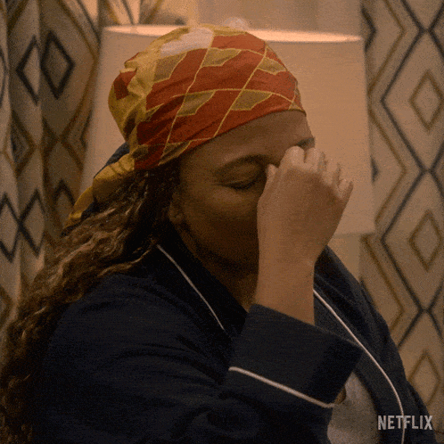 a woman wearing a head scarf is covering her face with her hand and a netflix logo can be seen in the background