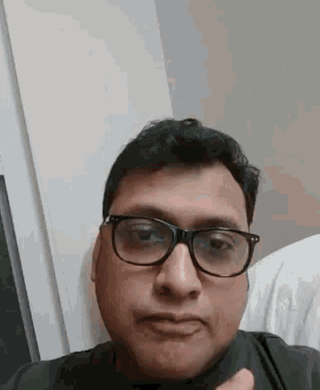 a man wearing glasses is making a funny face while giving a thumbs up .