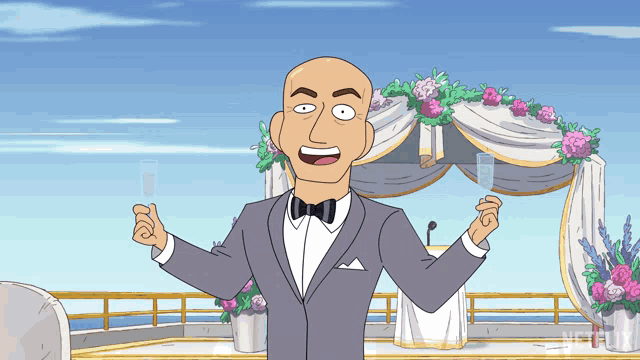 a bald man in a tuxedo holds a glass of champagne