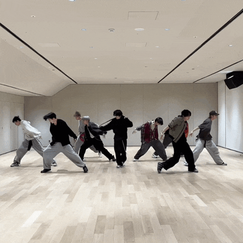 a group of young men are dancing together in a large room