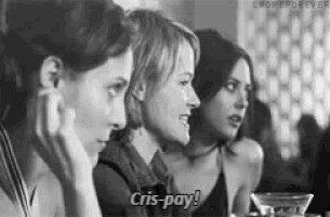 a black and white photo of three women sitting at a table . one of the women is saying `` cris-pay '' .