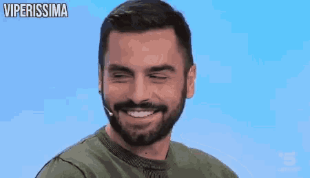a man with a beard is smiling and wearing a microphone on his head .