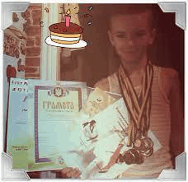 a young boy is holding a certificate and medals with a cake in the background .