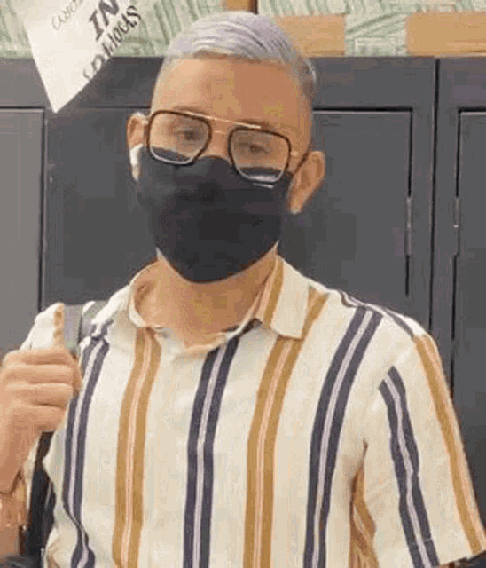 a man wearing a mask and glasses is holding a backpack .