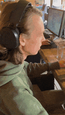 a man wearing headphones sits in front of a computer screen