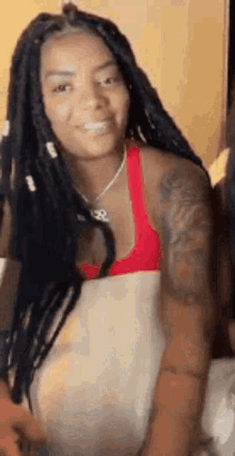 a woman with dreadlocks is sitting on a bed with a pillow .