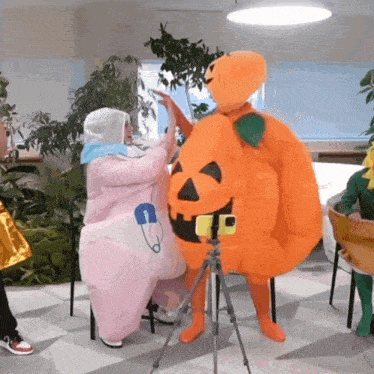 a person in a pumpkin costume takes a picture of another person in a baby costume