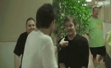 a group of men are standing in a hallway and talking to each other .