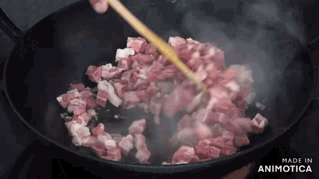 a pan of meat is being stirred with a wooden spoon and the words made in animotica are on the bottom