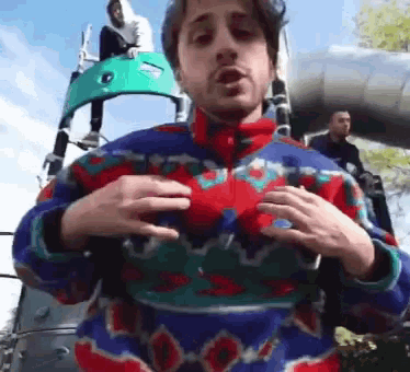 a man in a colorful sweater is standing in front of a slide