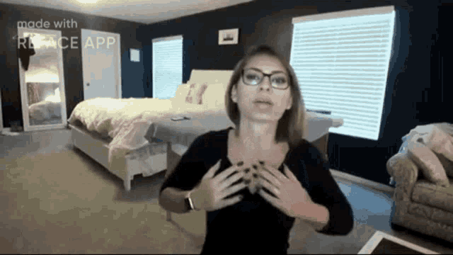 a woman wearing glasses and a black shirt is standing in a bedroom with the words made with reface app on the bottom