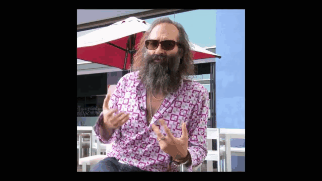 a man with a beard wearing sunglasses and a pink shirt