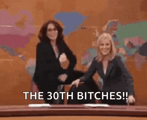 two women are dancing in front of a sign that says `` the 30th bitches ! ''