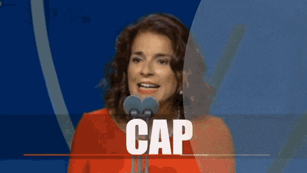 a woman in a red shirt is speaking into a microphone with the word cap behind her