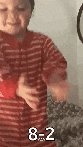 a young boy in a red and white striped shirt is holding a red object in his hands .