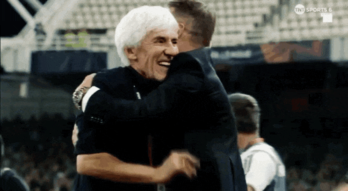 two men hugging on a soccer field with tnt sports 6 on the bottom