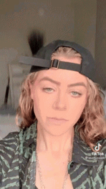 a woman is wearing a baseball cap and a zebra print shirt .
