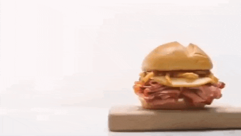 a sandwich is sitting on a wooden cutting board