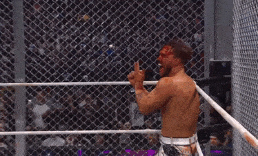a wrestler with blood on his face stands in a ring