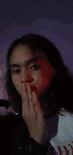 a man with long hair covering his mouth with his hands